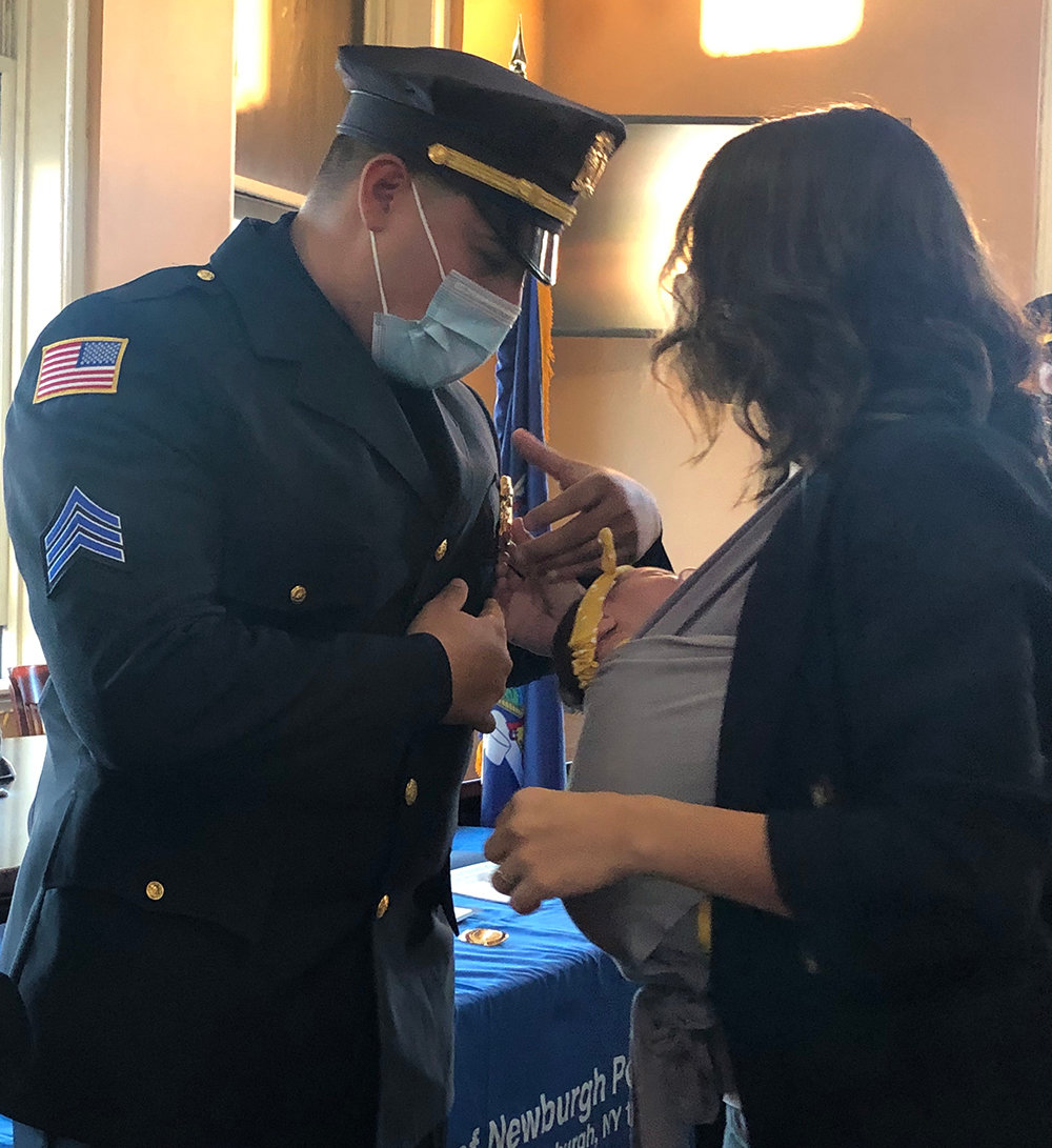 Sergeant Angelo Yonnone receives his new badge pinned by his wife.
